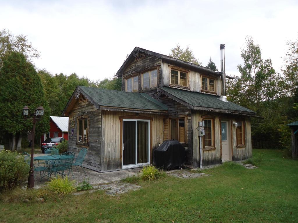 a small wooden house with a porch in a yard at Chalet Saint-Thomas in LʼAnse-Saint-Jean