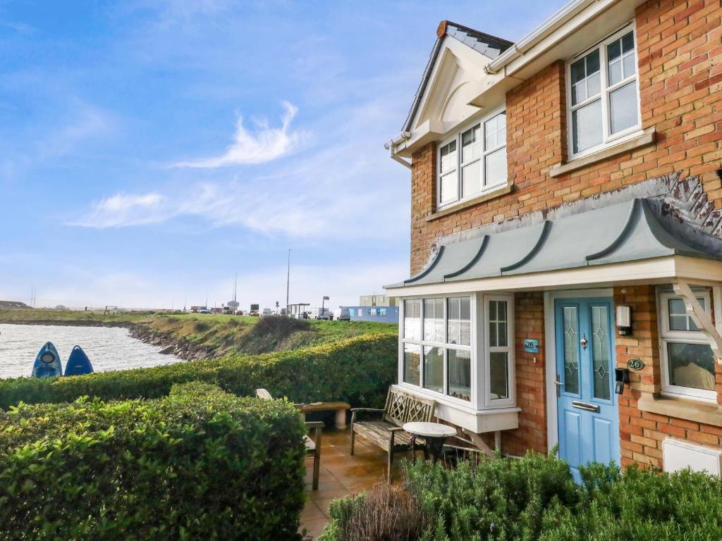 a brick house with a blue door next to the water at Still Waters in Wyke Regis