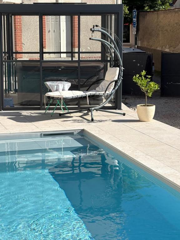 a swimming pool with a bench and a chair next to it at Entre Loire et Zoo Chambres d hôtes in Meusnes