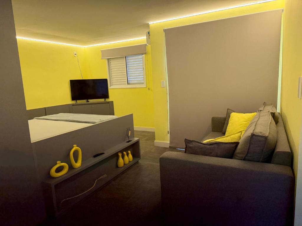 a bedroom with a bed and a couch and a tv at Flat Red Sorocaba - Yellow in Sorocaba