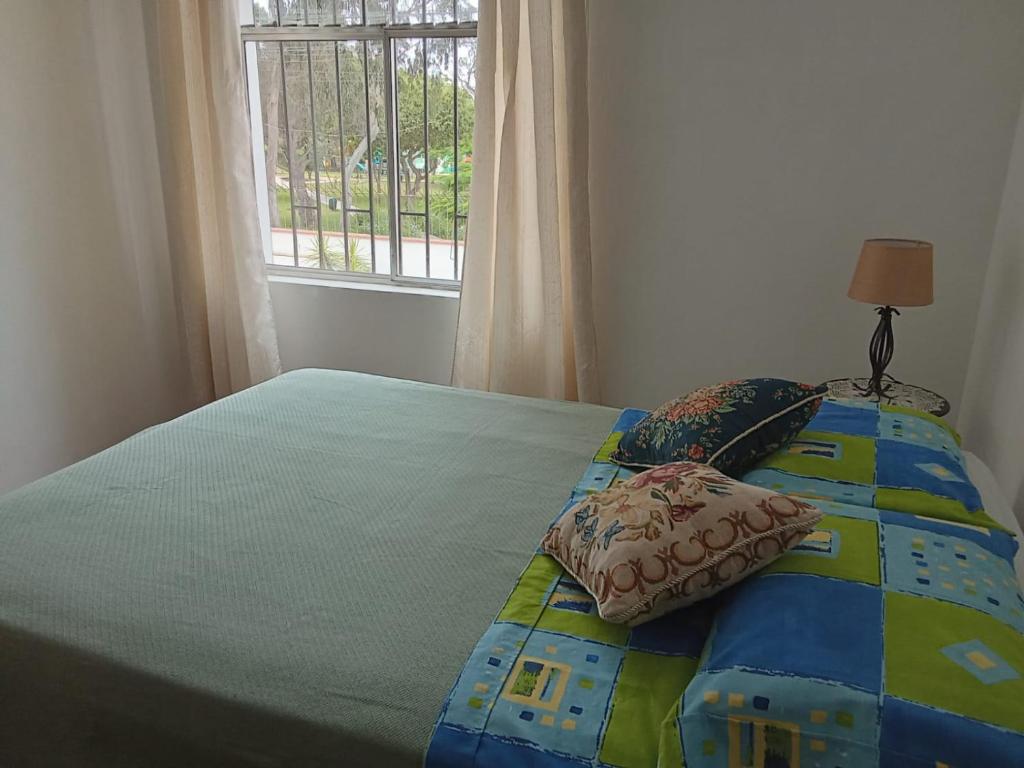 a bedroom with a bed with a quilt and a window at KUSIHaus in Lima
