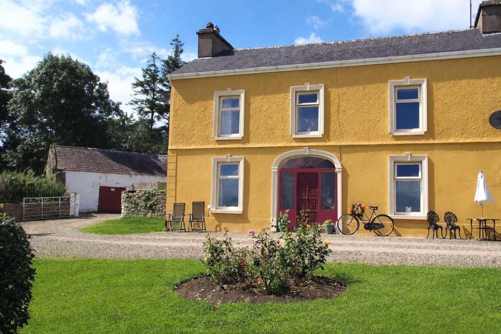 a yellow house with a red door at Shannonview Country House in Labasheeda