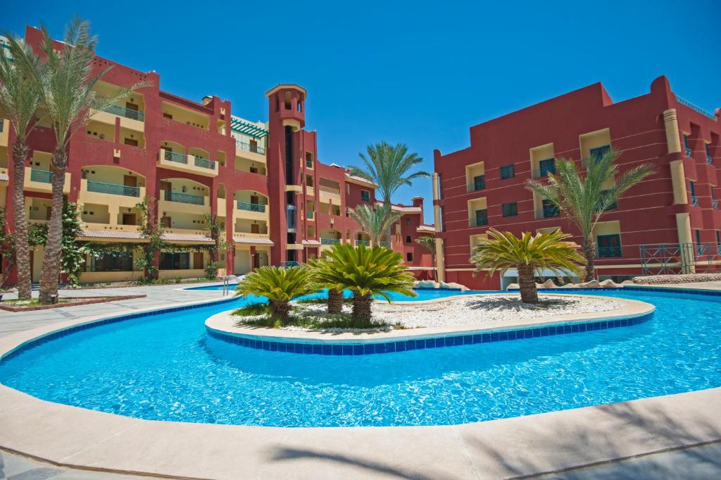 Sun & Sea Hotel and Aqua Park - Hurghada في الغردقة: مسبح امام مبنى فيه نخيل