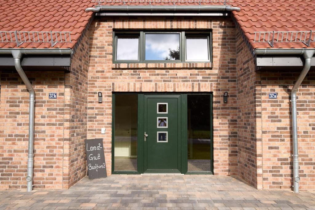 a brick building with a green door and a window at Landgut Basthorst in Crivitz