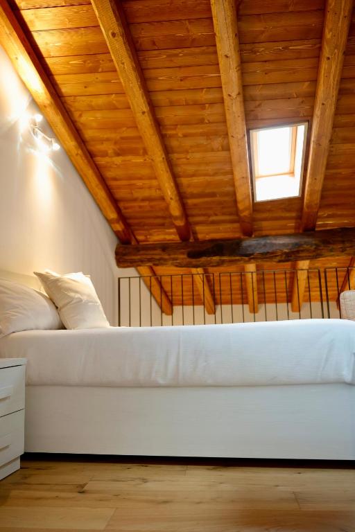 a bedroom with a white bed with a wooden ceiling at Piazza del Lago Suites - Menaggio in Menaggio