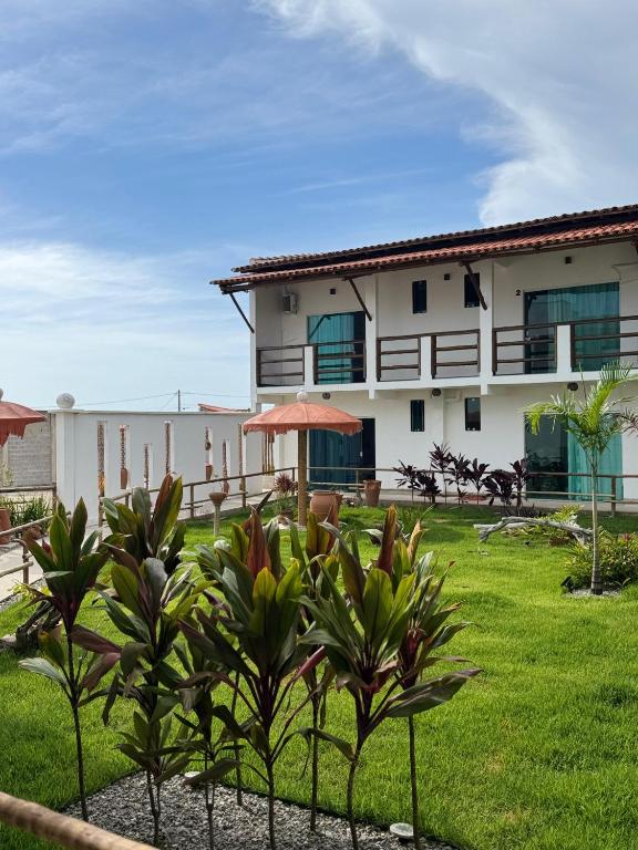 a building with plants in front of a yard at Pousada Flor De Prado in Prado