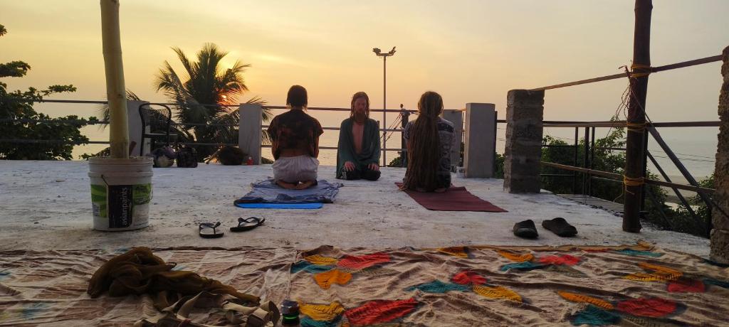 a group of girls sitting on the beach watching the sunset at Funky Art Beach House in Alleppey