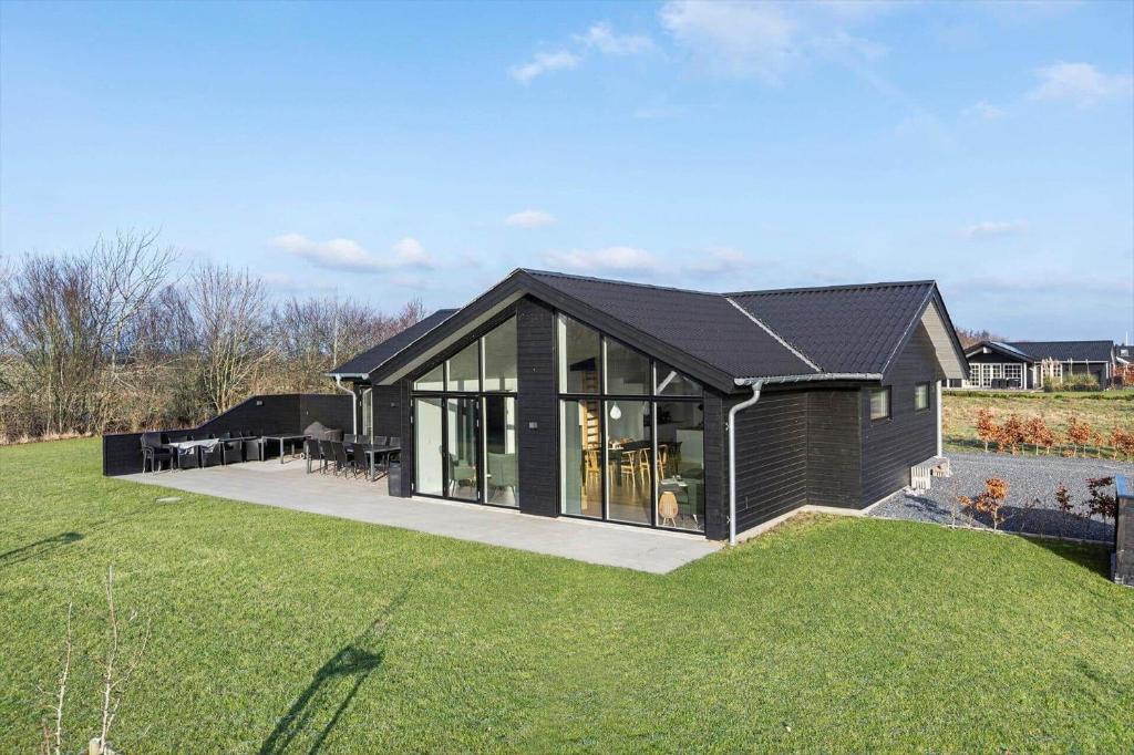 a house with a black roof on a grass field at SB128-Krusa-Hyldemose-23 in Skovbyballe