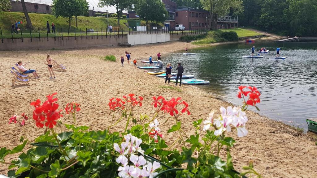 a group of people on a beach near the water at Gruppenunterkunft am Waldsee in Krefeld