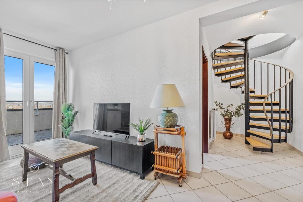 a living room with a spiral staircase and a table at Appartement à Schifflange in Schifflange