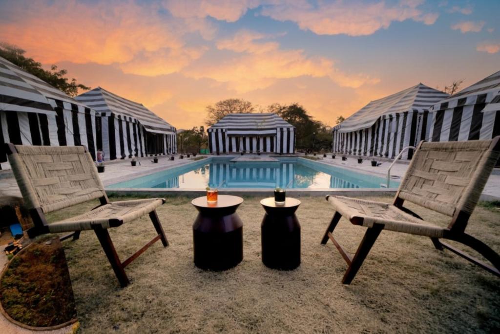 two chairs and a table in front of a pool at Badi Meadows By Wilkisto Near Fatehsagar Lake in Udaipur
