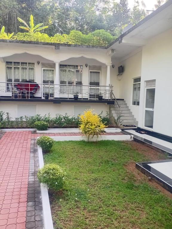 a white house with a lawn in front of it at Hotel Diamond Palace in Bibile