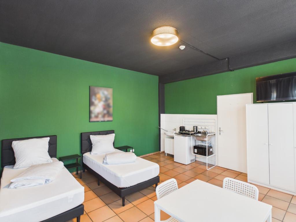 a room with two beds and a green wall at CROWN LIVING Babylon Studios Lustenau - Studios nahe Messe und Schweizer Grenze, WLAN, kostenloser Parkplatz, Self Check-in, ideal für Geschäftsreisende und Feriengäste in Lustenau