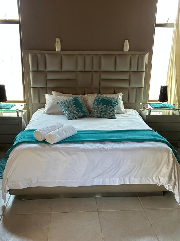 ein Schlafzimmer mit einem großen Bett und zwei Kissen in der Unterkunft Dorpsrus in Bela-Bela