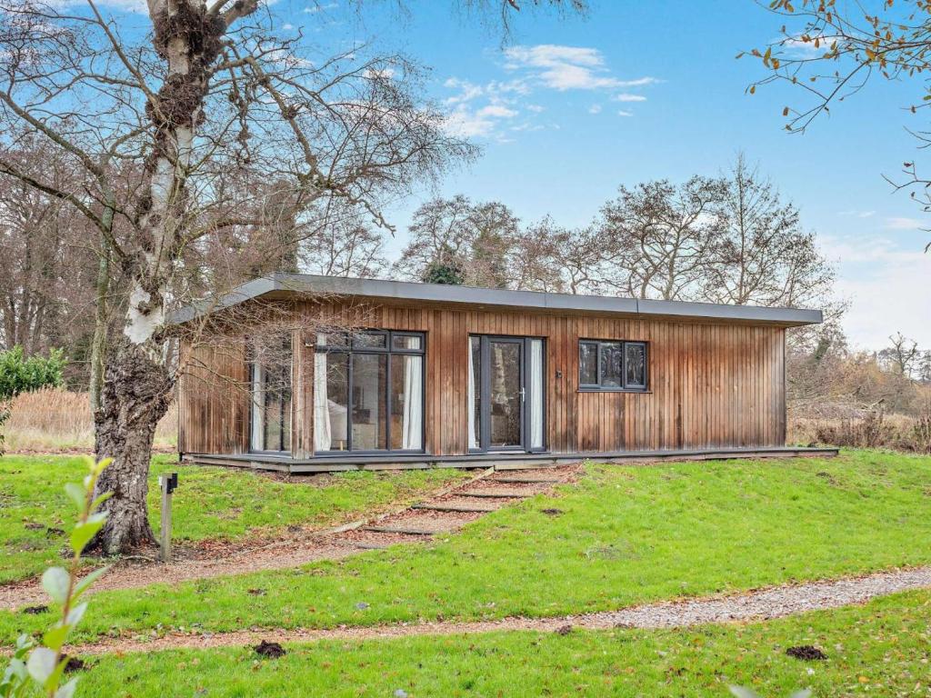 a small wooden house in a field with a tree at 2 Bed in Norwich oc-73624 in East Harling