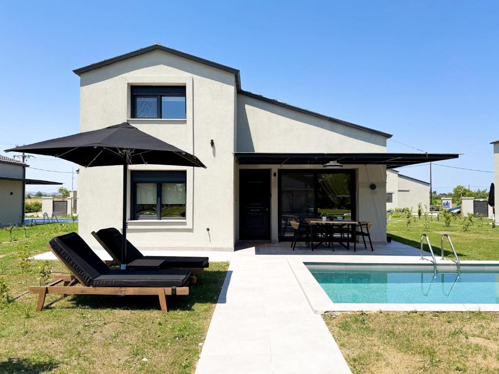 a house with a pool and two chairs and an umbrella at Ammos Luxury Pool Villas in Olympic Beach