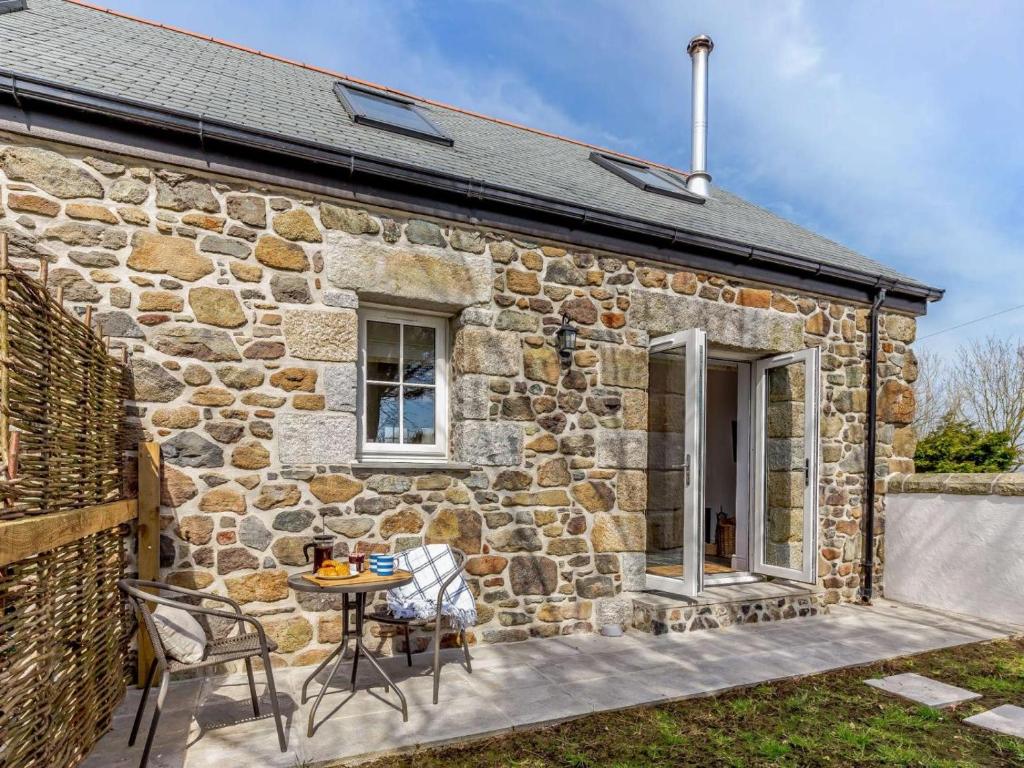 a stone cottage with a table and chairs in front of it at 1 Bed in Helston oc-82496 in Ruan Minor