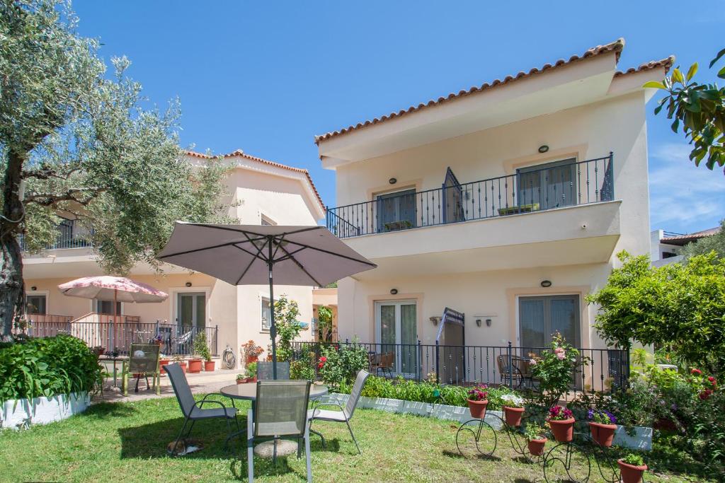 a villa with a garden and a table with an umbrella at Syrainas studios in Troulos