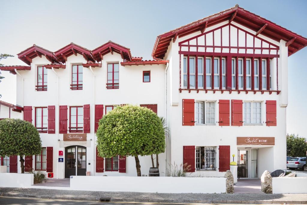 a large white building with red shutters at Hôtel Briketenia in Guéthary