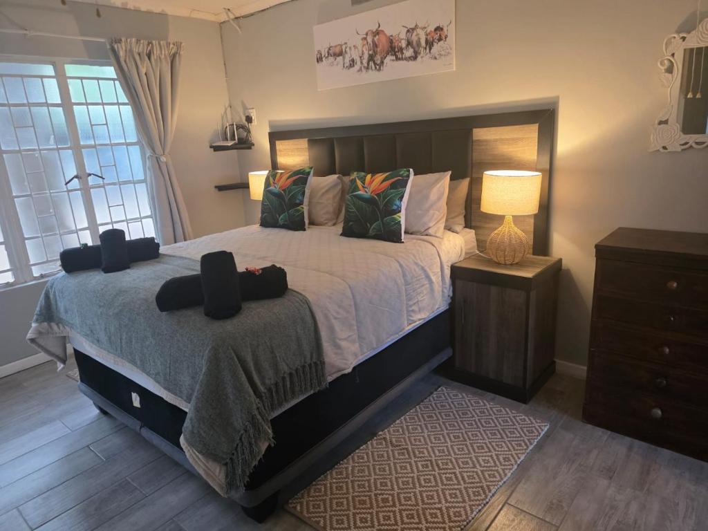 a bedroom with a bed with a lamp and a dresser at Nguni Rest in Barberton