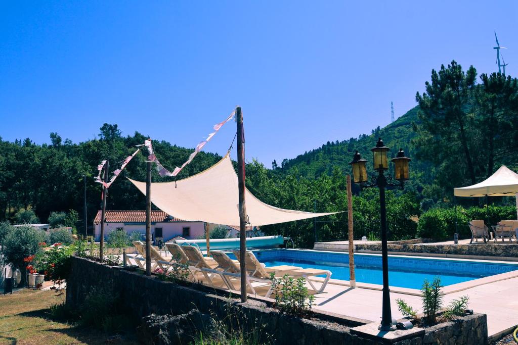 a group of lounge chairs with a tent by a pool at Quinta Cabecinha in Penela