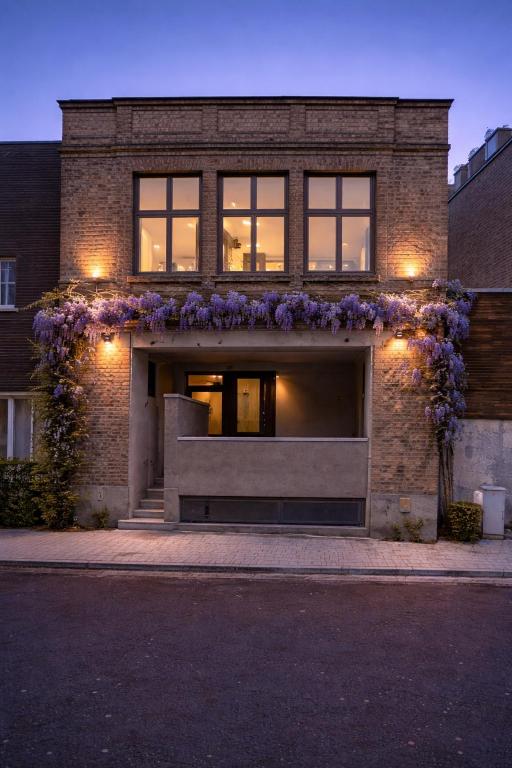 a brick building with purple flowers on it at Burgschelde 61 in Oudenaarde
