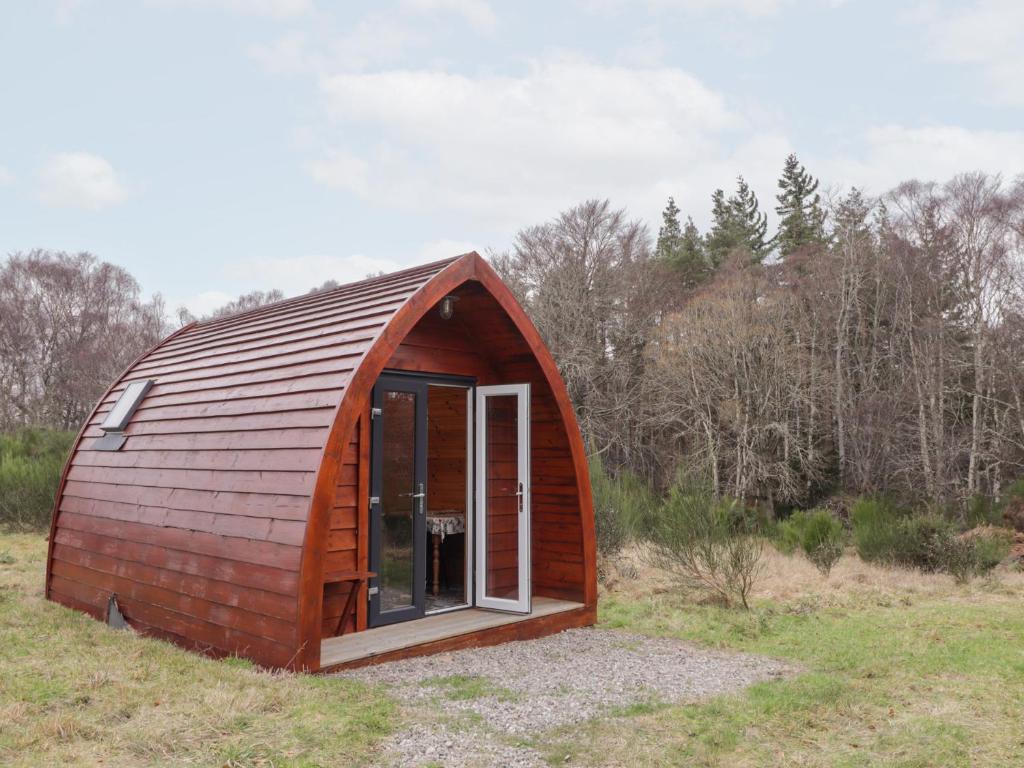 a small red barn with a window in a field at Pod 1 in Belladrum