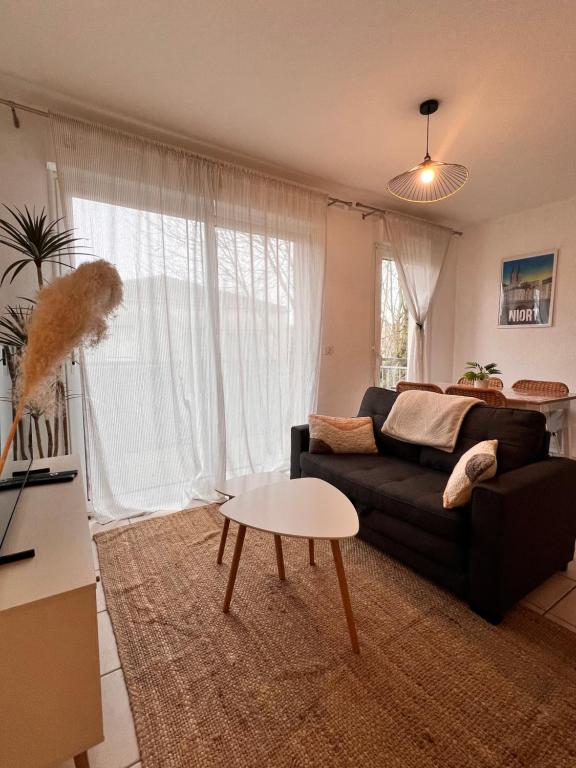 a living room with a black couch and a table at Le bohème Chauraisien in Chauray