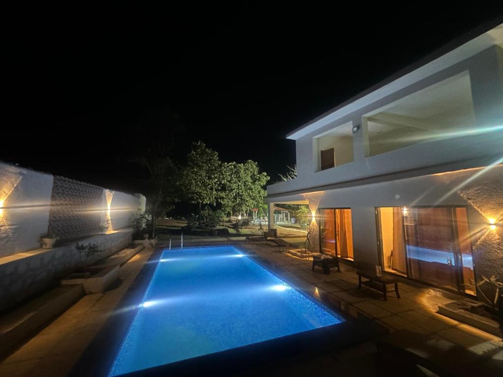 a villa with a swimming pool at night at Moksha farms -3bhk private villa with pool and nature in Pālghar