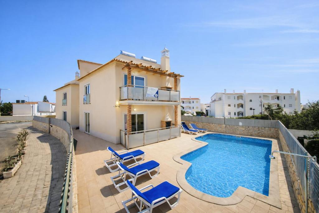 a villa with a swimming pool and some blue chairs at Oura Oasis D - Shared Pool - 4 Guests - Albufeira in Albufeira