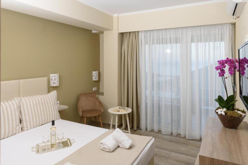 a hotel room with a white table and a window at Ammos Beach Seaside Luxury Suites Hotel in Olympic Beach