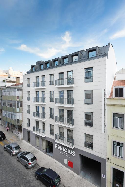 a white building with cars parked in a parking lot at Fenicius Charme Hotel in Lisbon