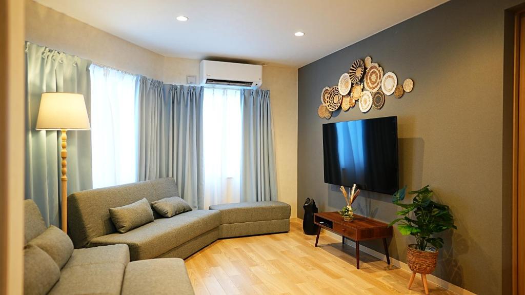 a living room with a couch and a tv at Cloud House Sapporo in Sapporo