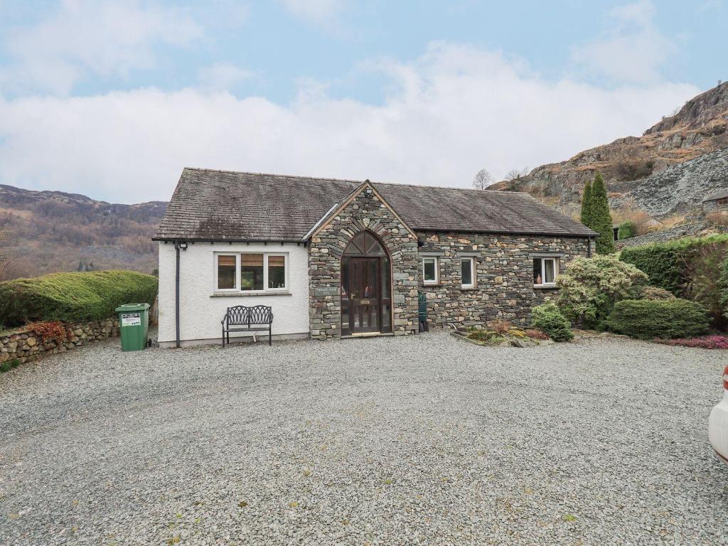 a stone house with a bench in a gravel driveway at Thrang View in Ambleside