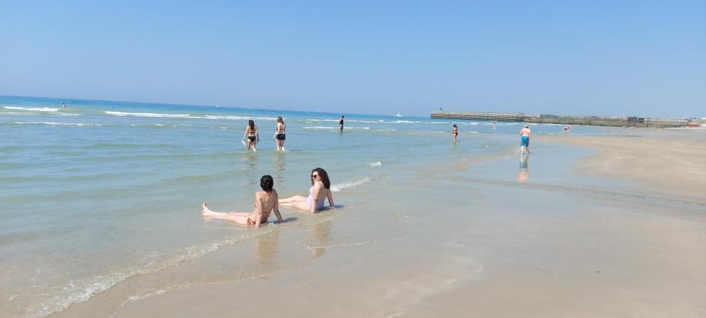 two women sitting in the water on the beach at Dieppe Appartement Vue plage et port in Dieppe