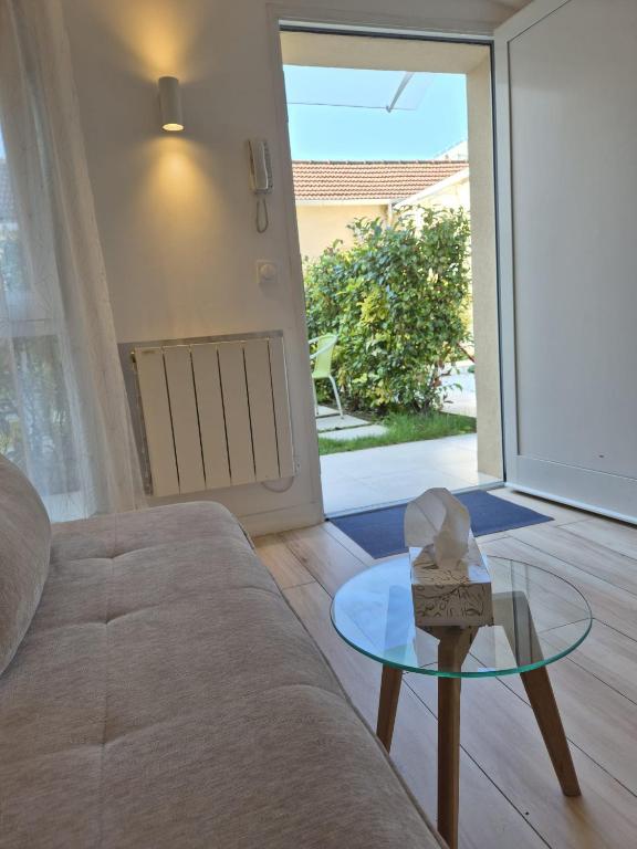 a living room with a couch and a glass table at Maison chaleureuse jacuzzi PS2-1, climatisation et parking payants in Bagneux