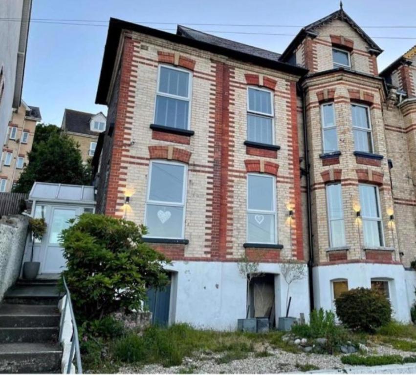 an old brick house with white doors and windows at The Devonshire Villa in Ilfracombe