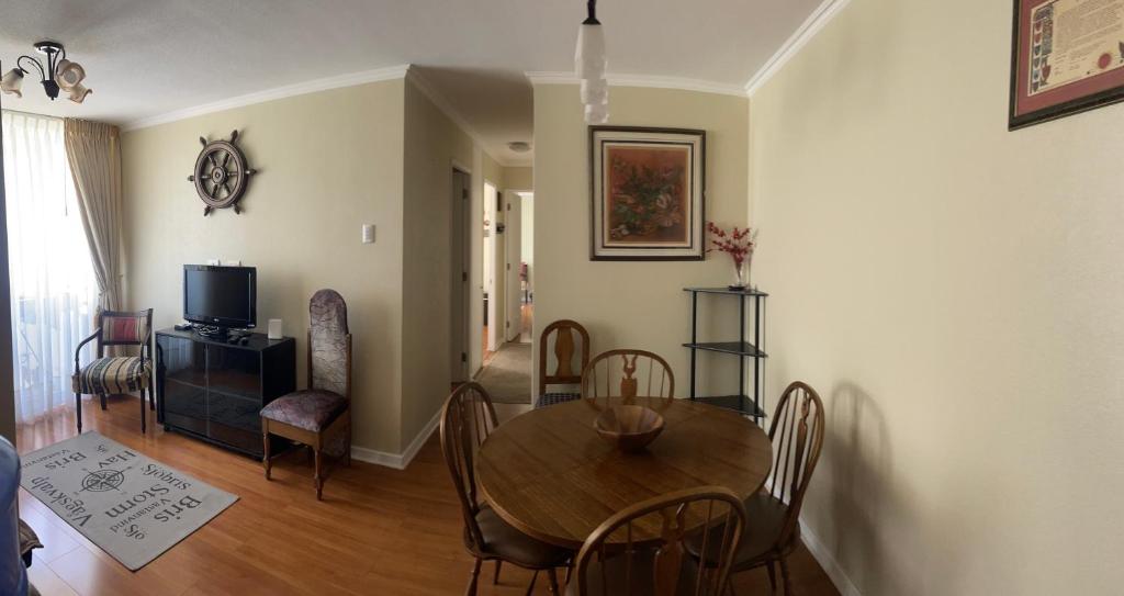 a living room with a table and chairs and a television at Departamento familiar in La Serena