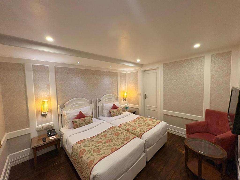 a bedroom with a large bed and a red chair at Hotel Bright in New Delhi
