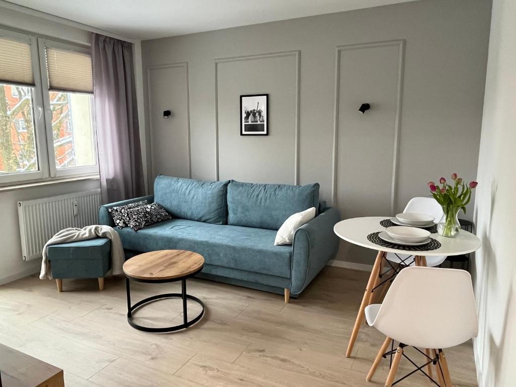 a living room with a blue couch and a table at Apartament Jedenastka in Kraśnik