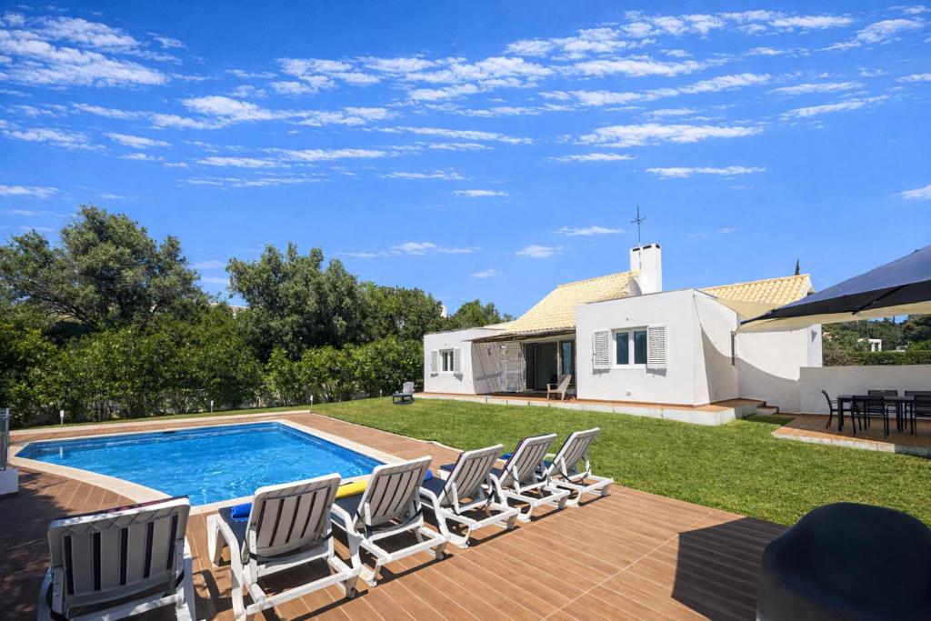 a group of lounge chairs sitting next to a swimming pool at Galo - Private Pool - 8 Guests - Albufeira in Albufeira