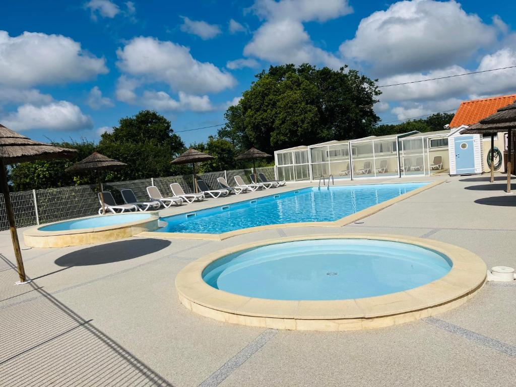 a large swimming pool with chairs and a building at Camping Le Roc in Vairé