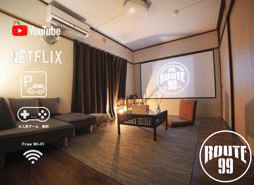 a living room with a couch and a screen at Route99 Yumoto 箱根湯本駅近山沿い川沿い 箱根湯本徒歩8分WIFI 大人気ゲーム機無料 最大6名 無料駐車場 in Hakone