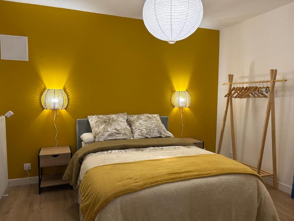 a bedroom with a bed with yellow walls and two lamps at Gite de la Moulette in Bergerac