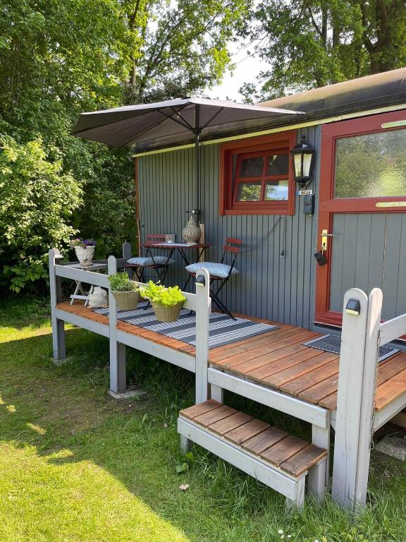 a house with a deck with a table and an umbrella at Romantischer Zirkuswagen in Edemissen
