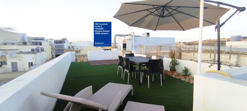 a balcony with a table and chairs and an umbrella at Charming Townhouse - Steps from Waterfront in Marsaxlokk