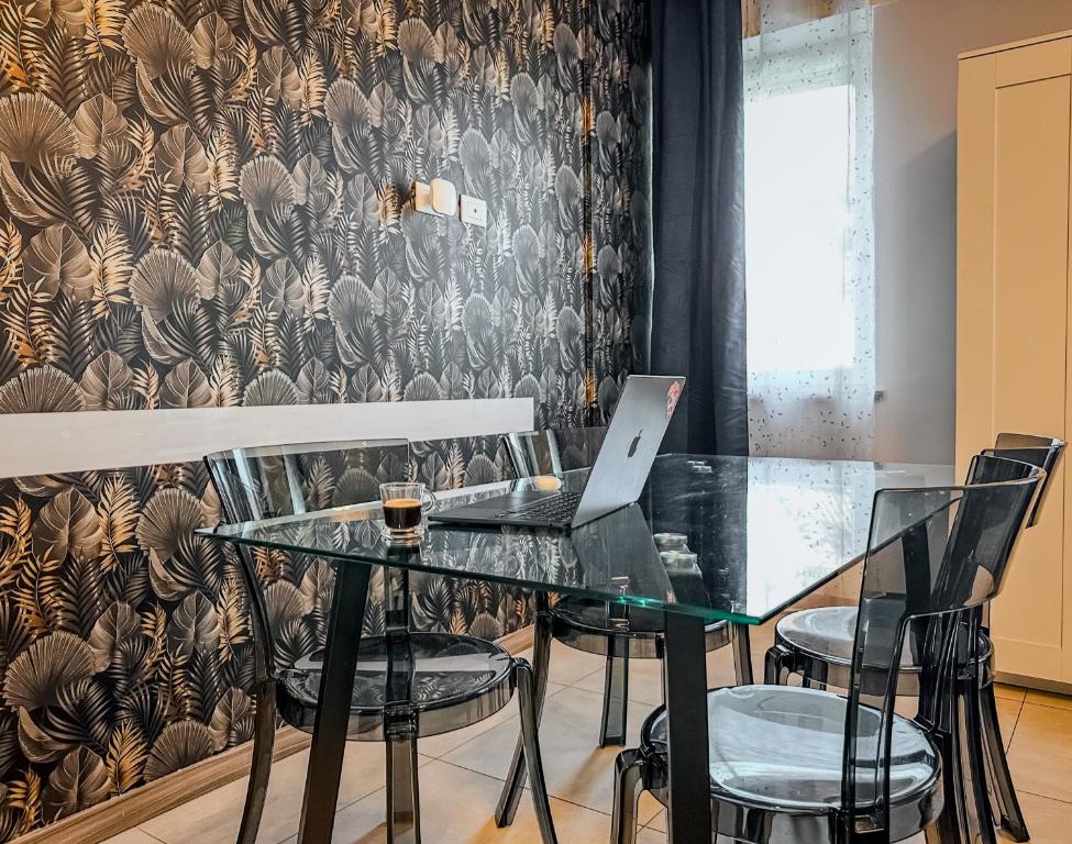 a dining room with a glass table with chairs and a laptop at Velvet Suite - Garage Privato - Metro Dante in Turin