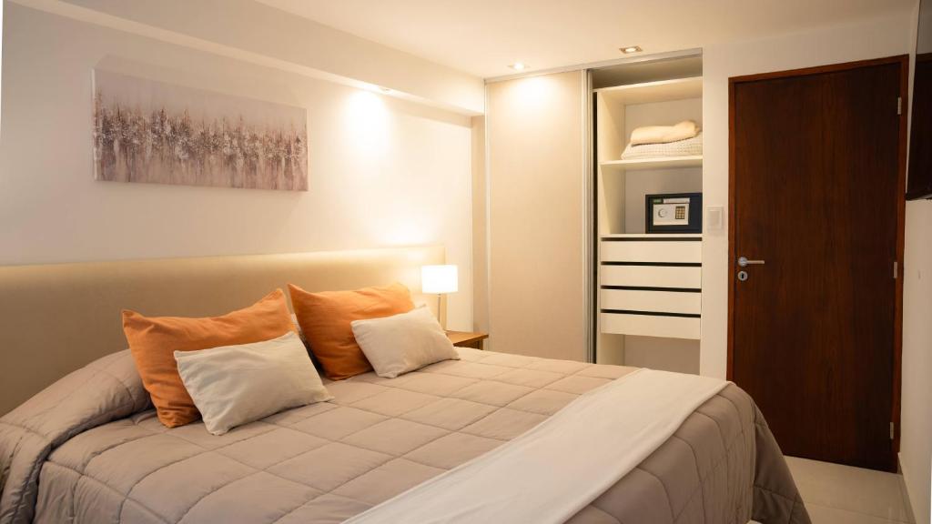 a bedroom with a bed with orange and white pillows at HOMEFULL Apartamentos in Salta