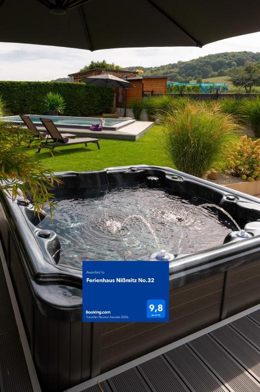 a hot tub in a yard with an umbrella at Ferienhaus Nißmitz No.32 in Freyburg