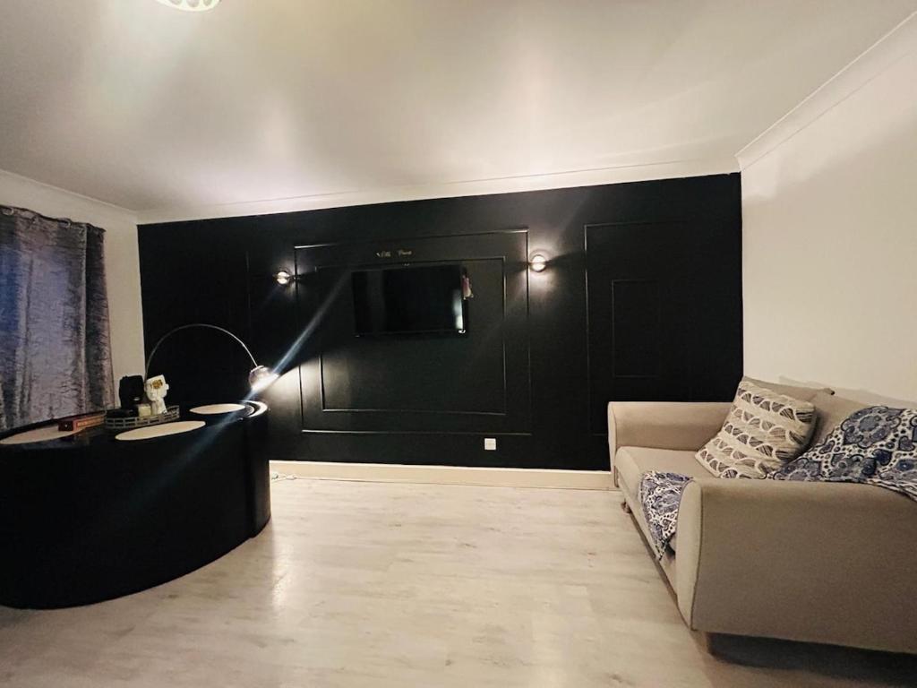 a living room with black walls and a couch at Modern & cozy 2 bedroom flat in Dundee
